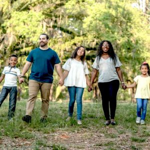 family of five holding hands and going for a walk in the park