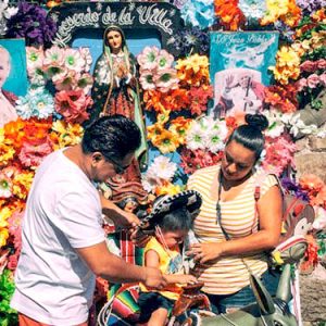 Hispanic family of three surrounded by colorful flower display