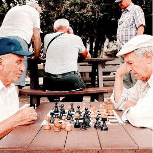 two aged men sitting at table playing a game of chess