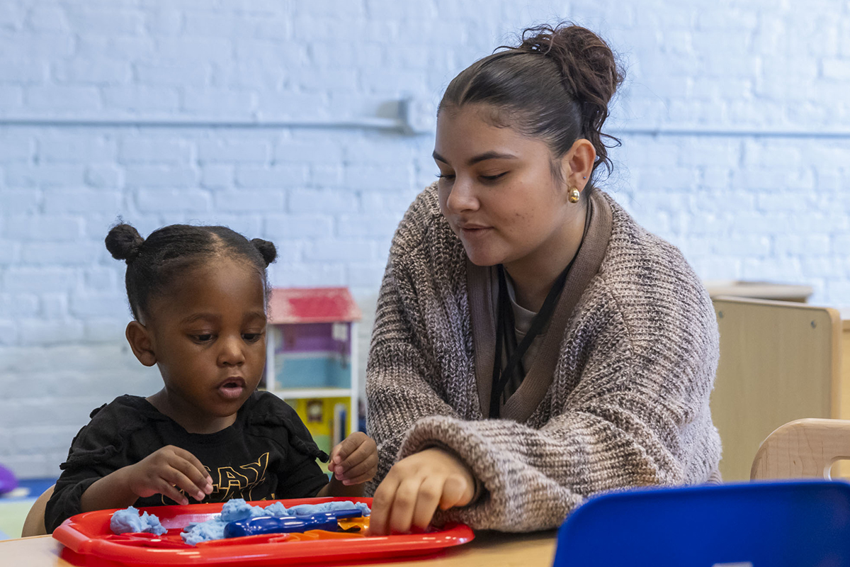 A student helping a child complete a hands-on activity in class.