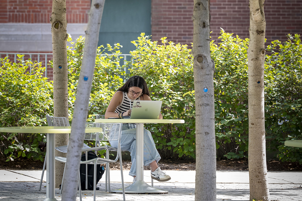 A student studying at a table outside.